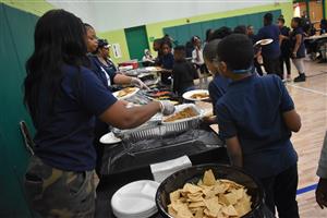 Students holding plates receiving nacho toppings